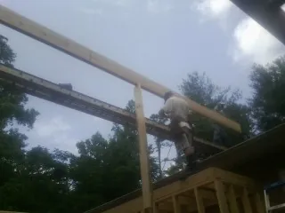 Carpenter setting a ridge beam over a new addition frame — Ice Dam Removal by Roofing Brothers in New Albany