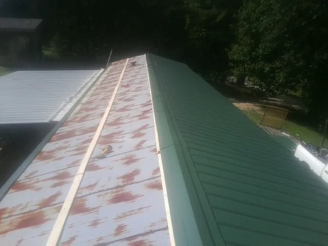 Old rusted panels beside newly installed green metal roofing — Wind Damage Roof Repair by Roofing Brothers in New Albany