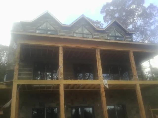 Dormers and porch framing on a large log home under construction — Roof Coating work by our crew in New Albany